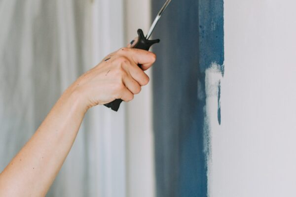 A closeup shot of a person using paint rollers with the color blue